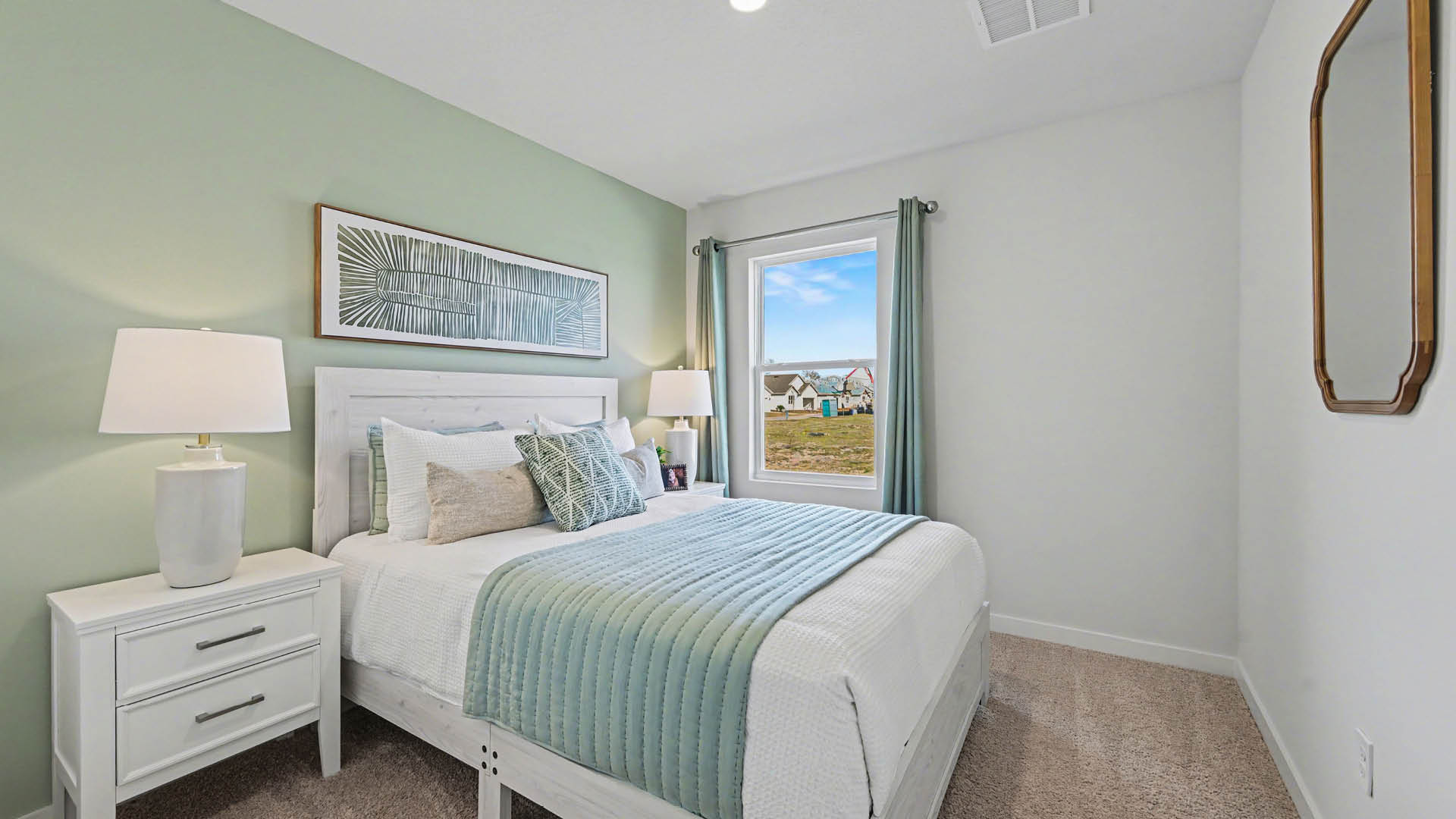 A bedroom with a bed, a window, and a painting on the wall. The room has white walls and beige carpet.