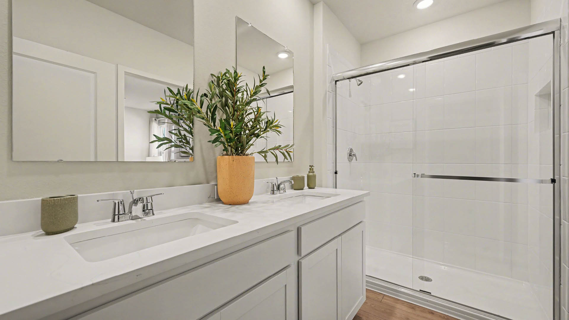 Spacious modern bathroom featuring a glass, walk-in shower, double sink vanity, and bright lighting.