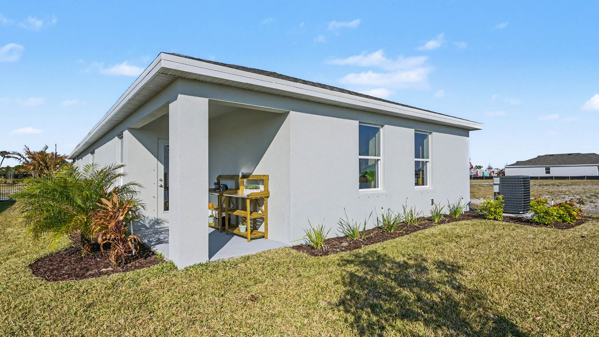 Rear view of a house featuring a stucco exterior, glass window door, and a covered patio.