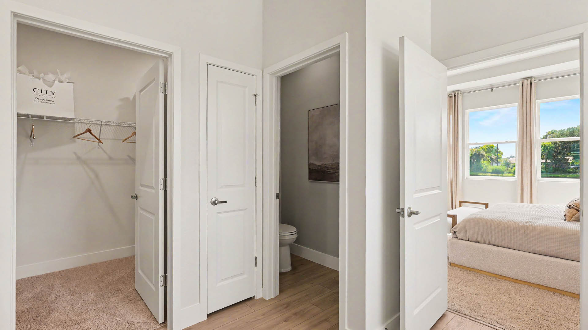 A bright bedroom with an open door leading to an ensuite bathroom and a walk-in closet.