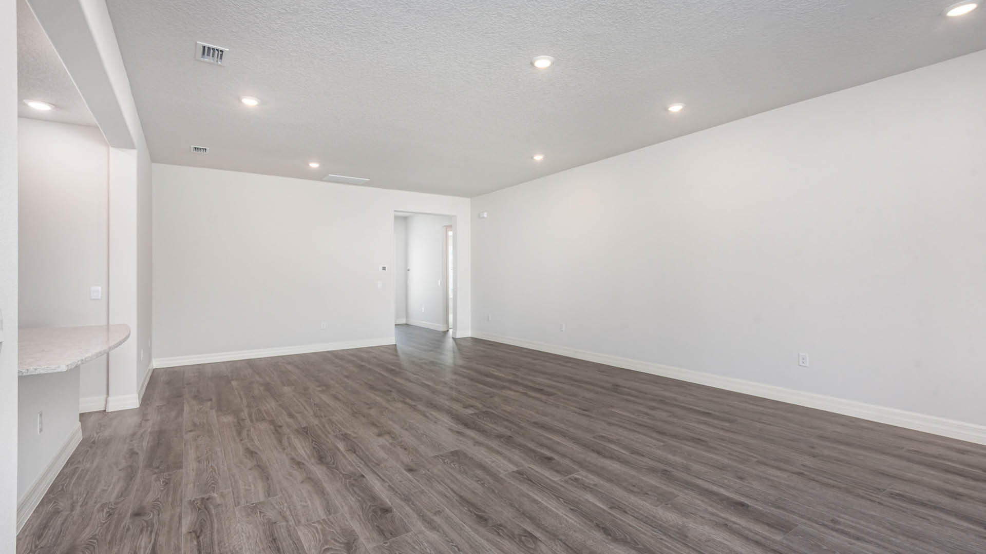 Modern living area with sleek vinyl plank floors, white walls.