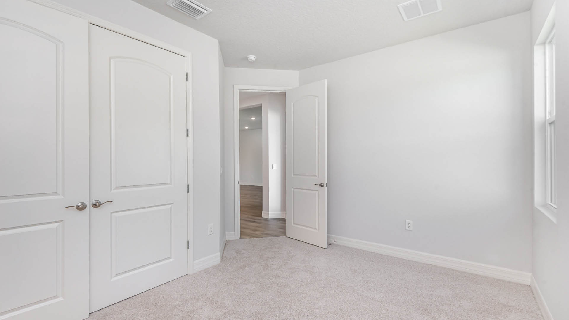 A clean, white room with two built-in closets and a single door, emphasizing simplicity and functionality.