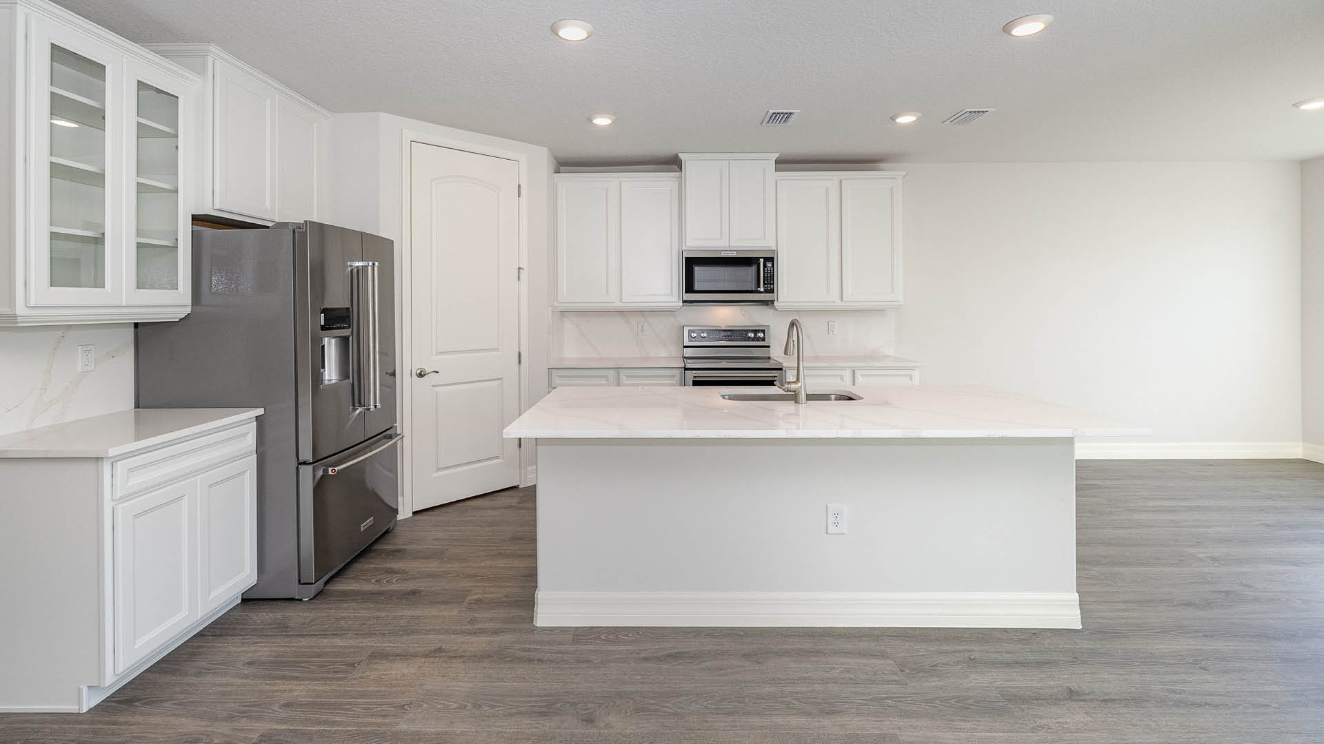 A large kitchen and dining area with quartz countertops, stainless steel appliances, and an island with room for seating.