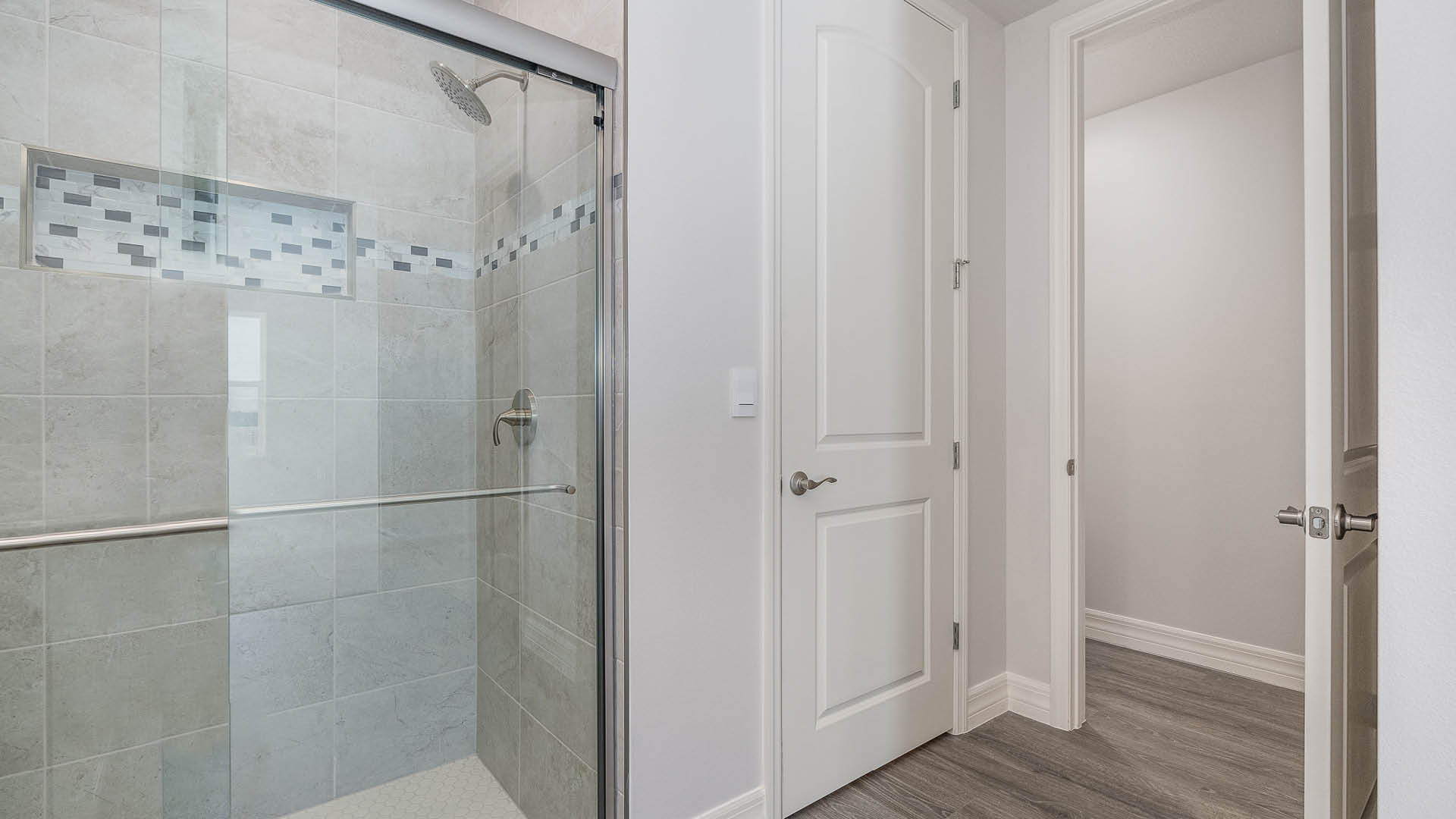 A spacious, ensuite bathroom featuring a walk-in shower. One closed door and one open door are visible.