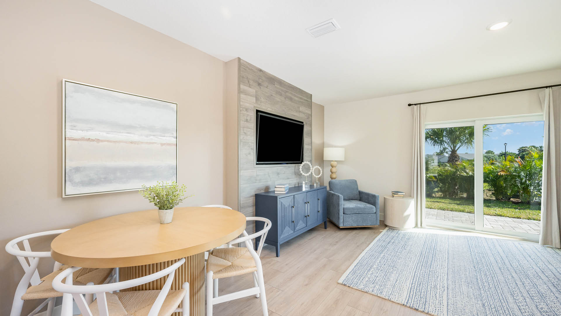 Modern living space featuring a round dining table, blue accent furniture, and large glass doors.
