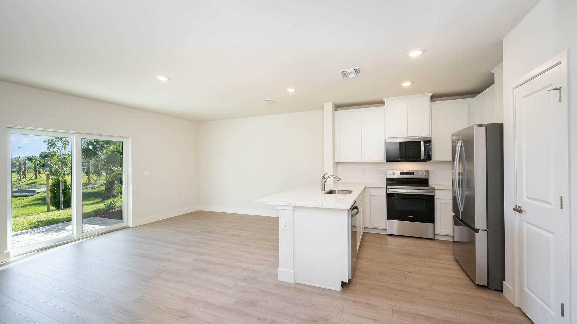 Modern kitchen featuring white cabinetry, stainless steel appliances, a large island with a sleek countertop, and bright lighting.