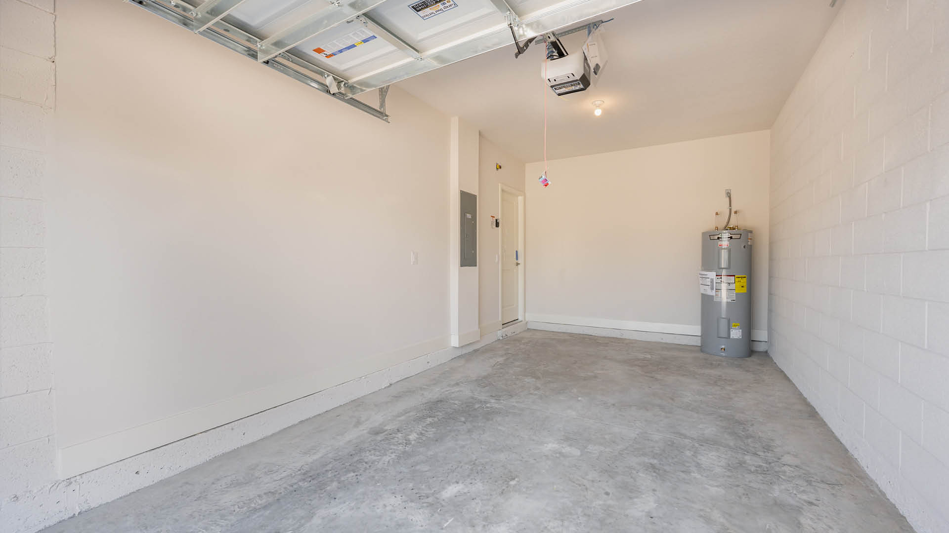 A clean garage with a light-colored block wall, polished flooring, and an automatic garage door opener mounted overhead.