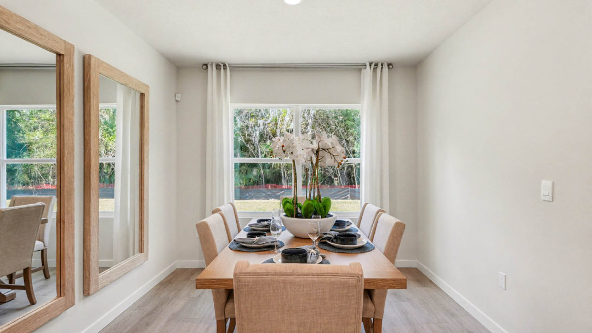 A dining room featuring a wooden table surrounded by four chairs, with soft lighting and a warm ambiance.