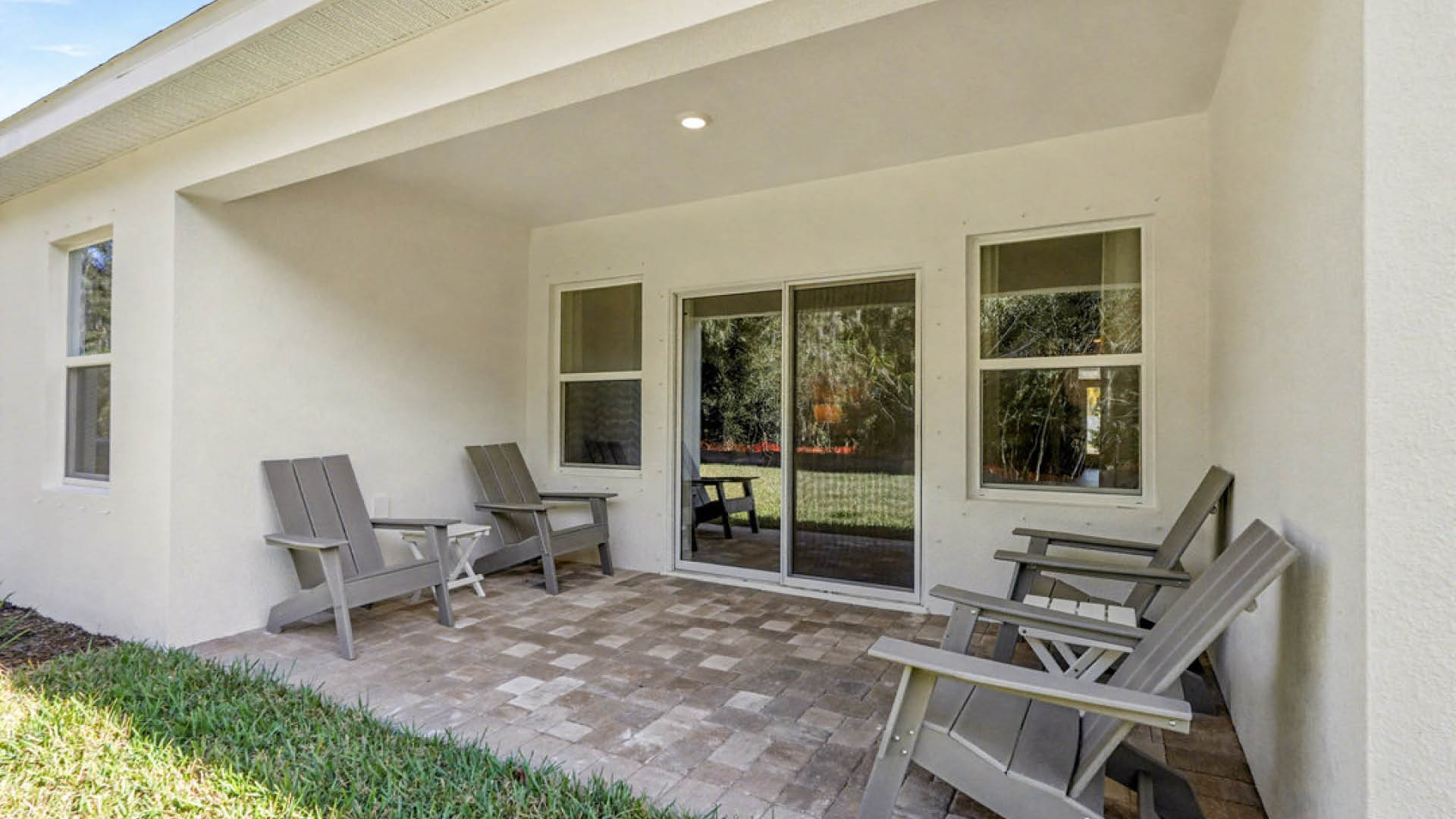 A patio featuring several chairs and a sliding glass door leading to the interior space.