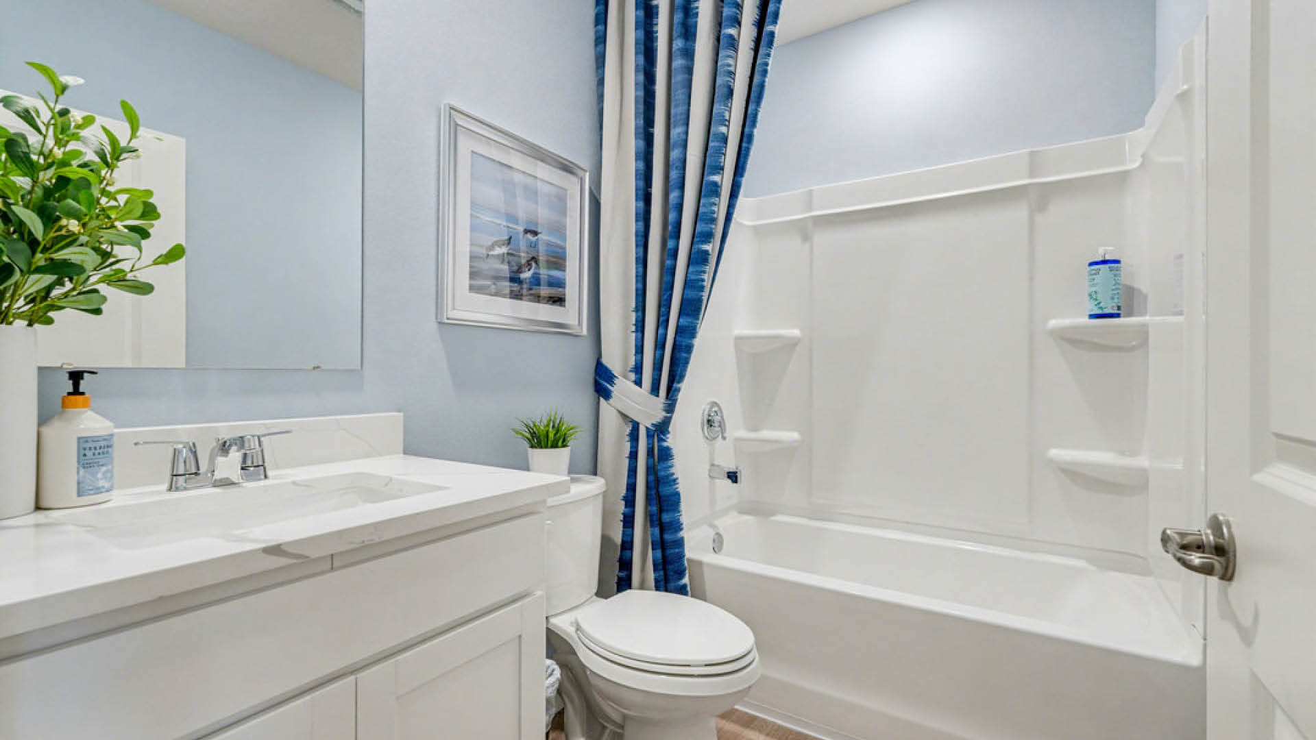 A bathroom featuring a blue shower curtain and a white toilet, creating a clean and simple aesthetic.