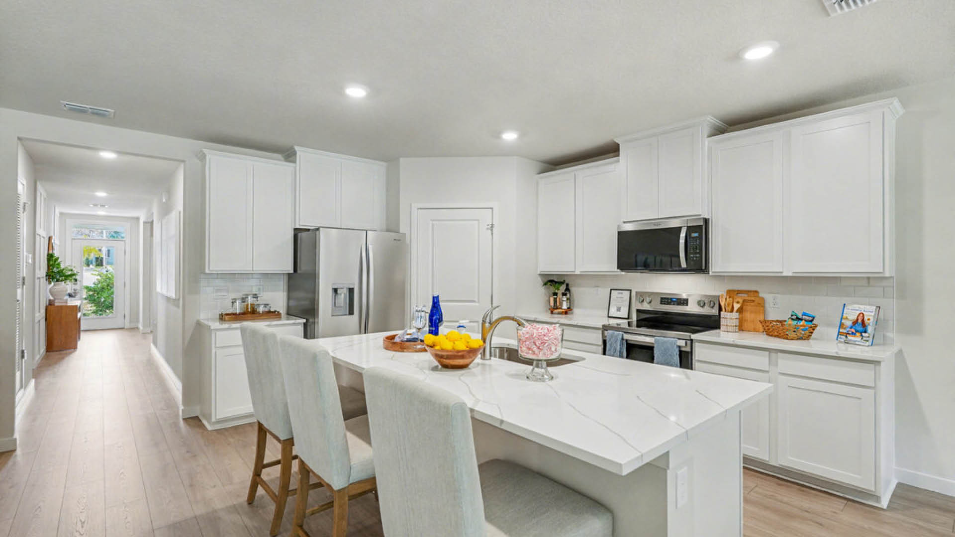 Bright, modern kitchen with white cabinets, stainless steel appliances, and a large quartz island.
