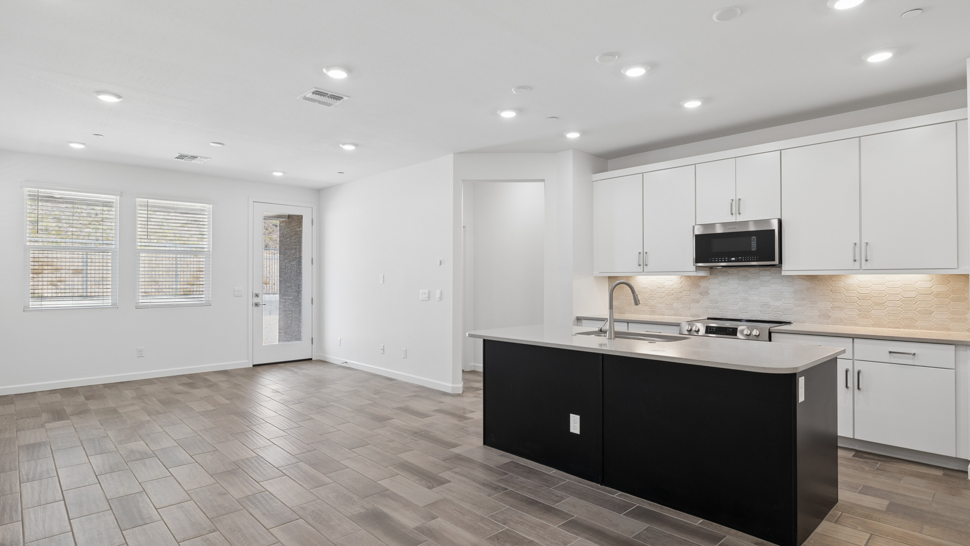 Bright and spacious kitchen with countertops, stainless steel appliances, and an island with bar seating.
