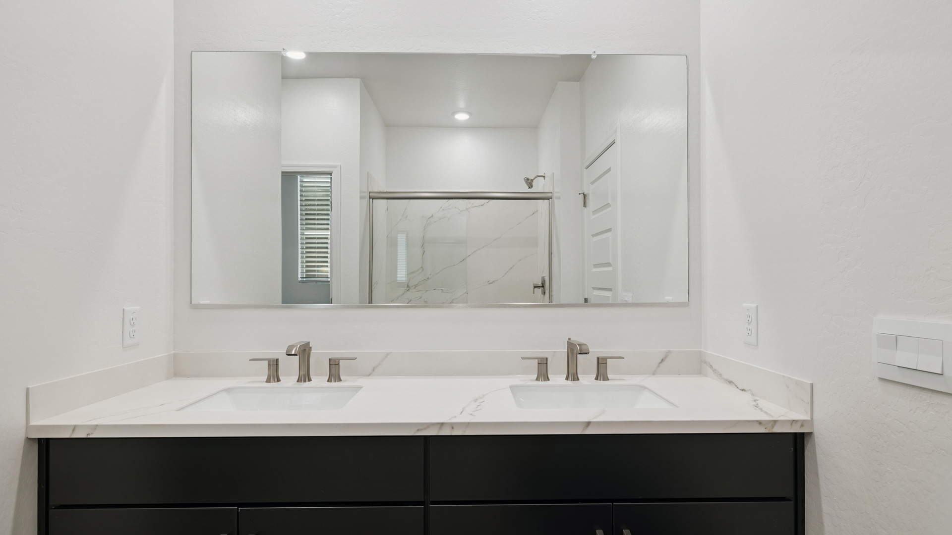 Modern primary bathroom with double vanities, countertops with a walk-in shower and a walk-in closet.