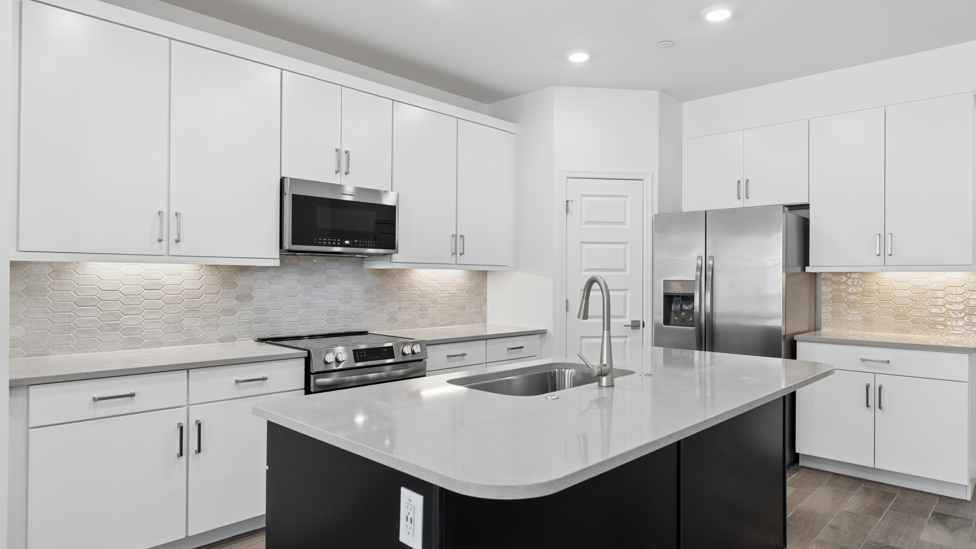 Bright and spacious kitchen with countertops, stainless steel appliances, and an island with bar seating.