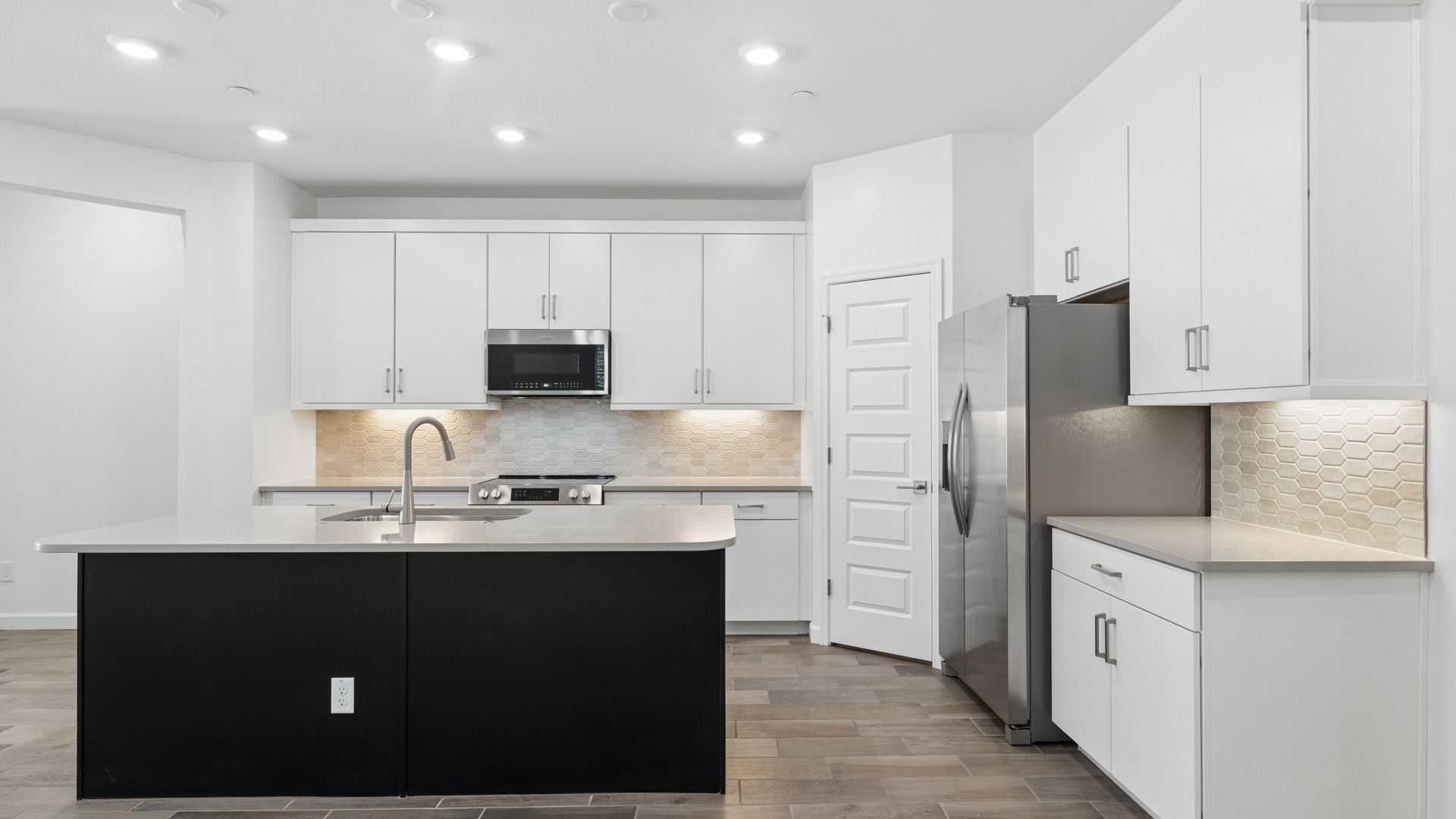 Bright and spacious kitchen with countertops, stainless steel appliances, and an island with bar seating.