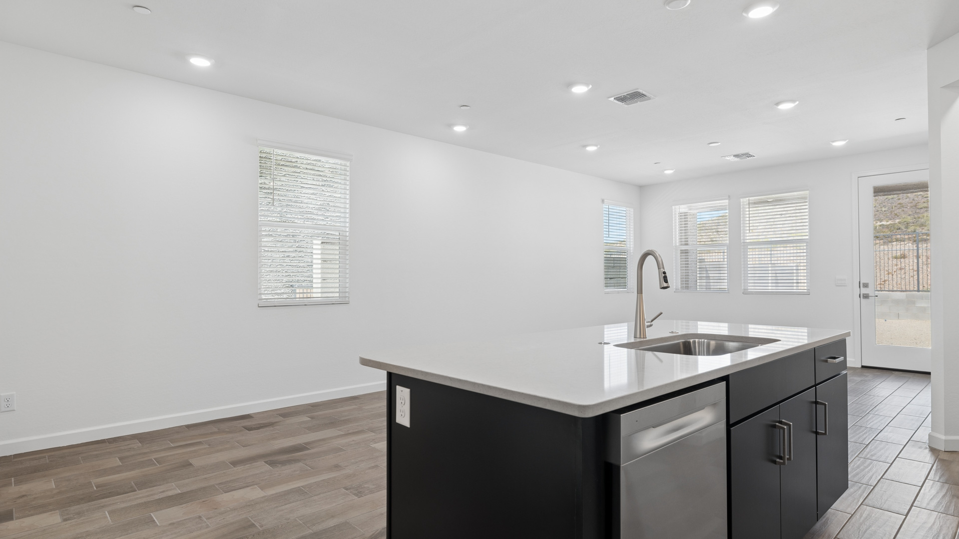 Bright and spacious kitchen with countertops, stainless steel appliances, and an island with bar seating.