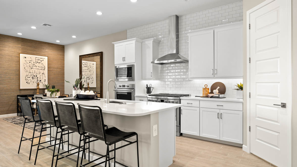 Bright and spacious kitchen with quartz countertops, stainless steel appliances, and an island with bar seating.