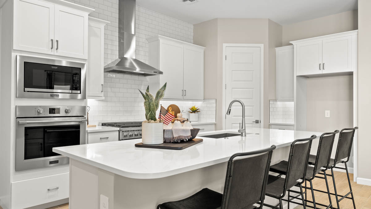 Bright and spacious kitchen with quartz countertops, stainless steel appliances, and an island with bar seating.