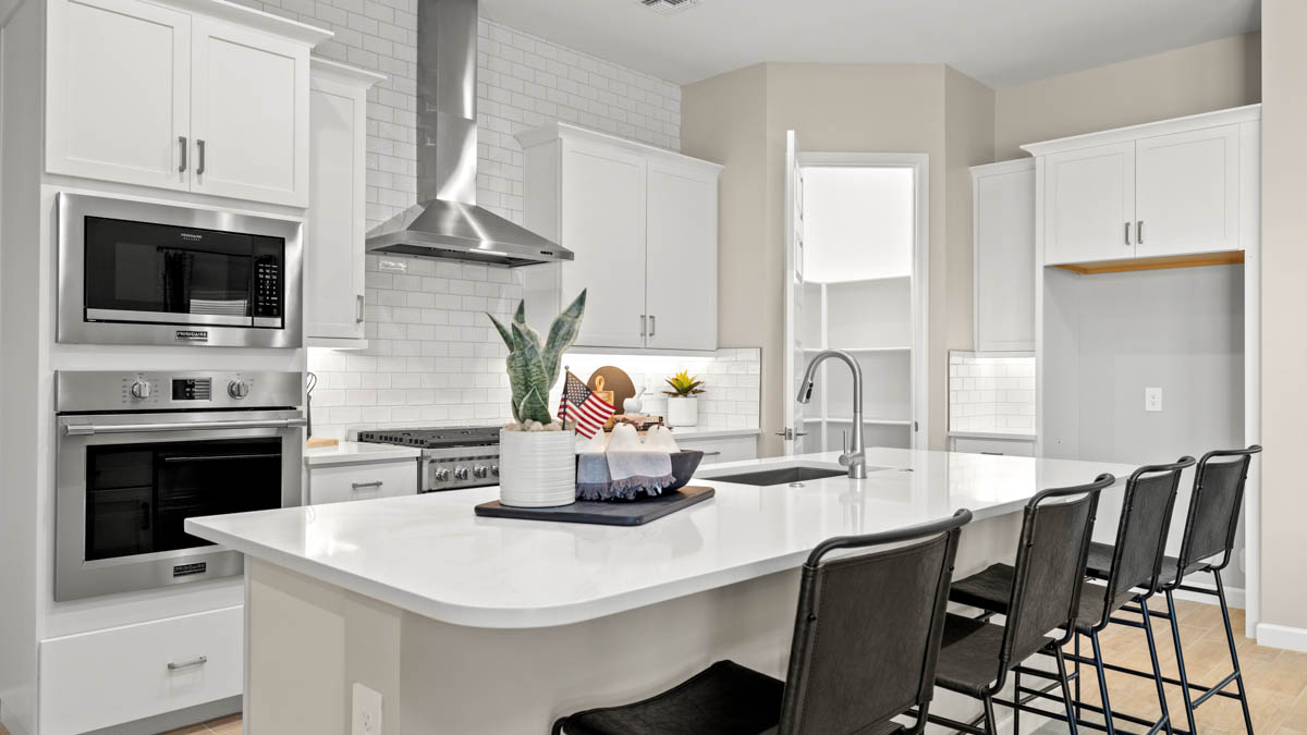 Bright and spacious kitchen with quartz countertops, stainless steel appliances, and an island with bar seating.