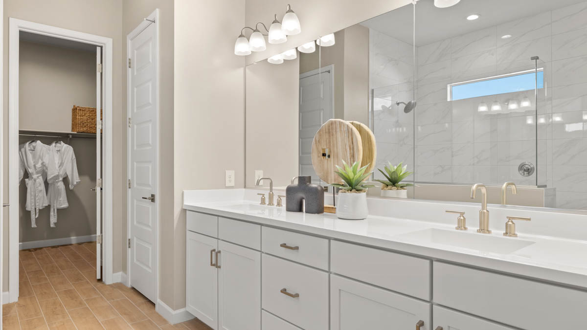 Modern primary bathroom with double vanities, quartz countertops with a walk-in shower and a walk-in closet.