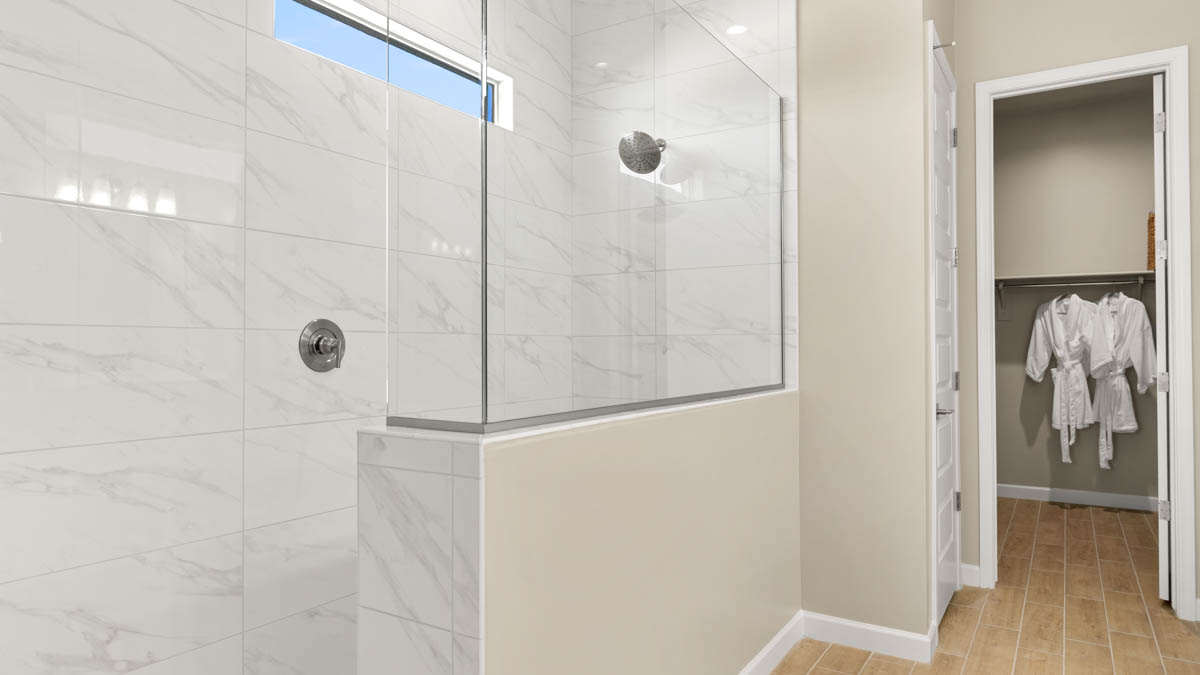 Modern primary bathroom with double vanities, quartz countertops with a walk-in shower and a walk-in closet.