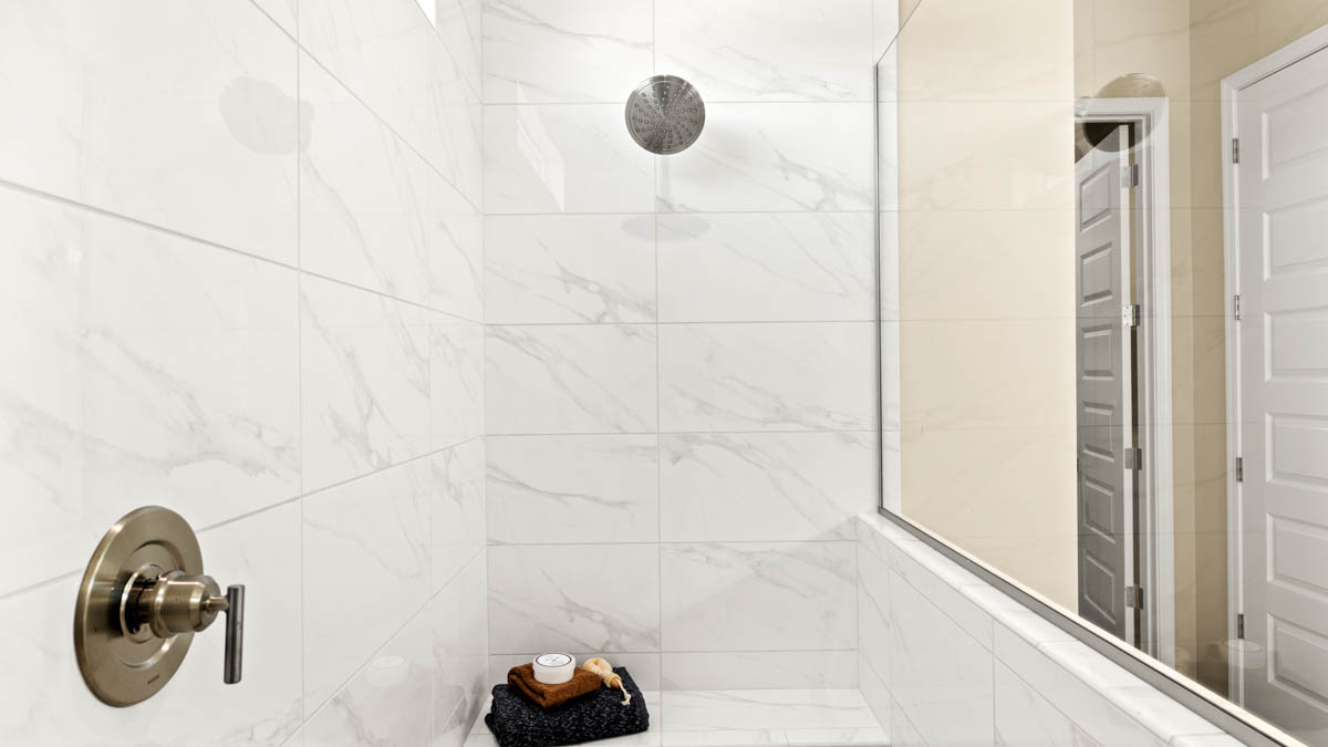 Modern primary bathroom with double vanities, quartz countertops with a walk-in shower and a walk-in closet.