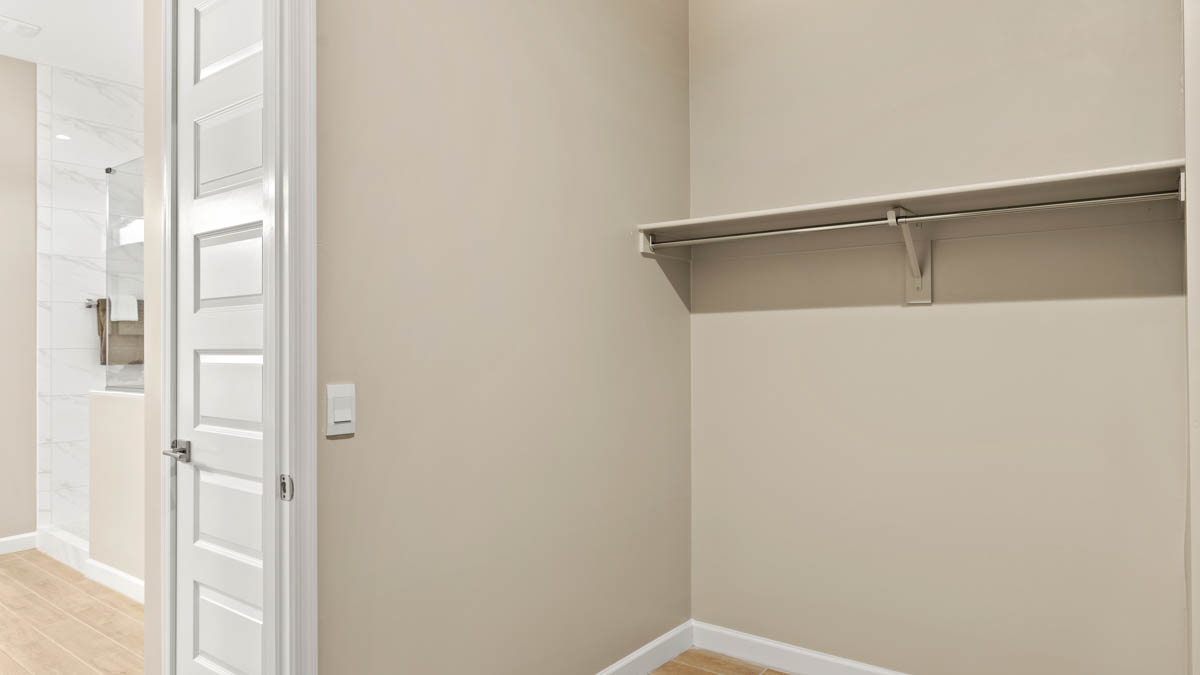 Modern primary bathroom with double vanities, quartz countertops with a walk-in shower and a walk-in closet.