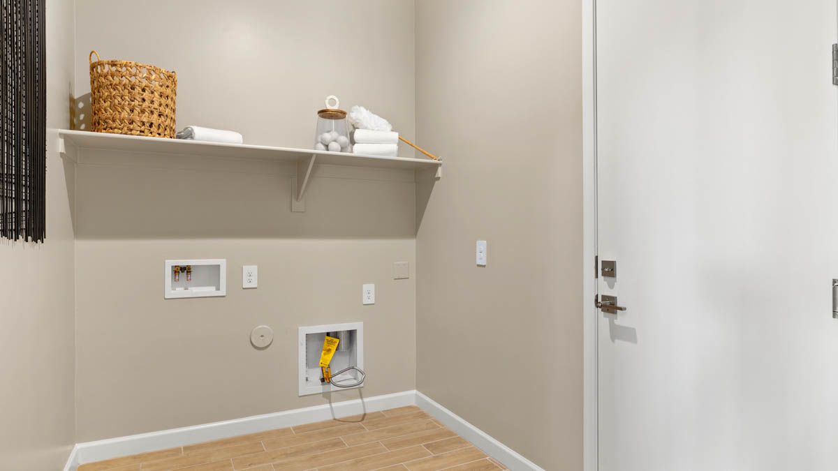 Spacious laundry room with washer and dryer connections and shelving for storage.
