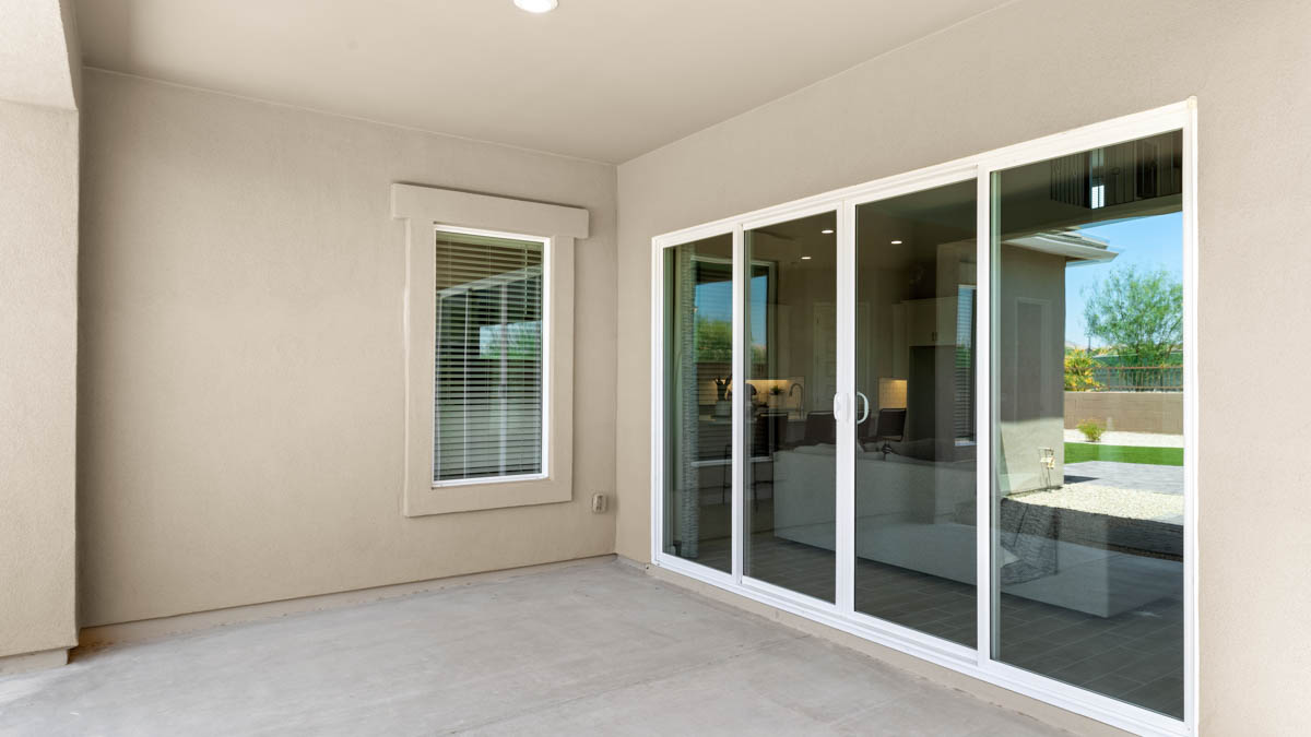 Outdoor covered patio with seating area overlooking a well-maintained lawn, perfect for relaxation.