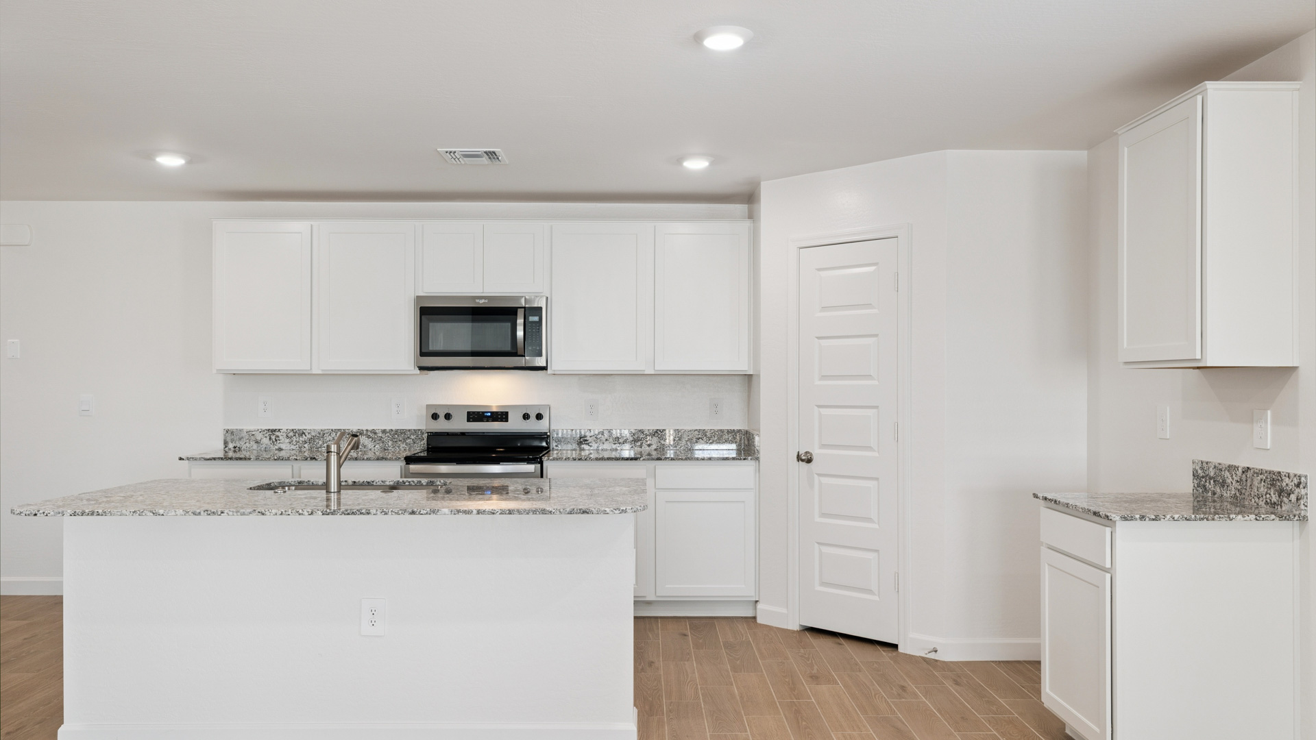 Bright and spacious kitchen with granite countertops, stainless steel appliances, and an island with bar seating.