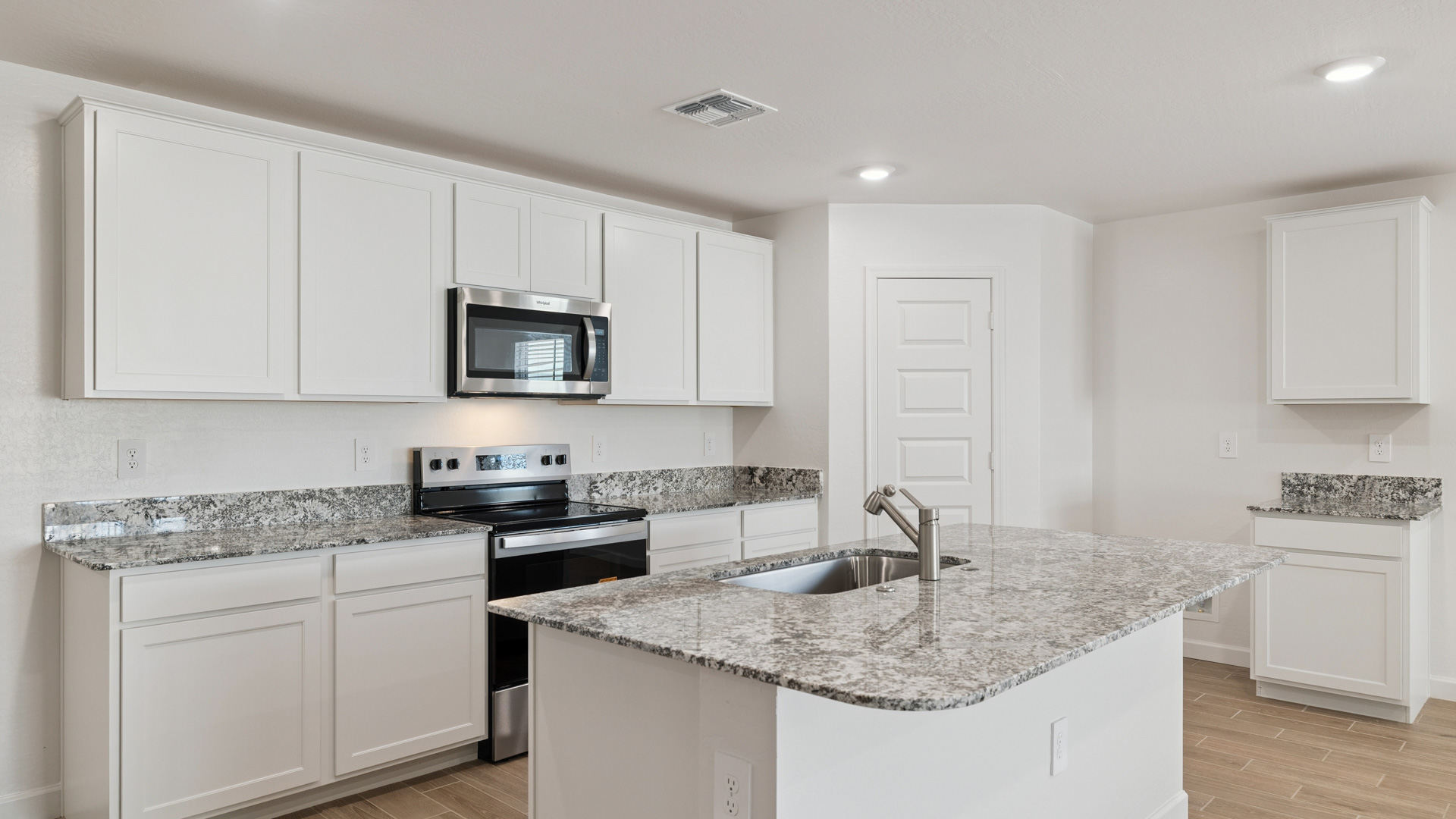Bright and spacious kitchen with granite countertops, stainless steel appliances, and an island with bar seating.