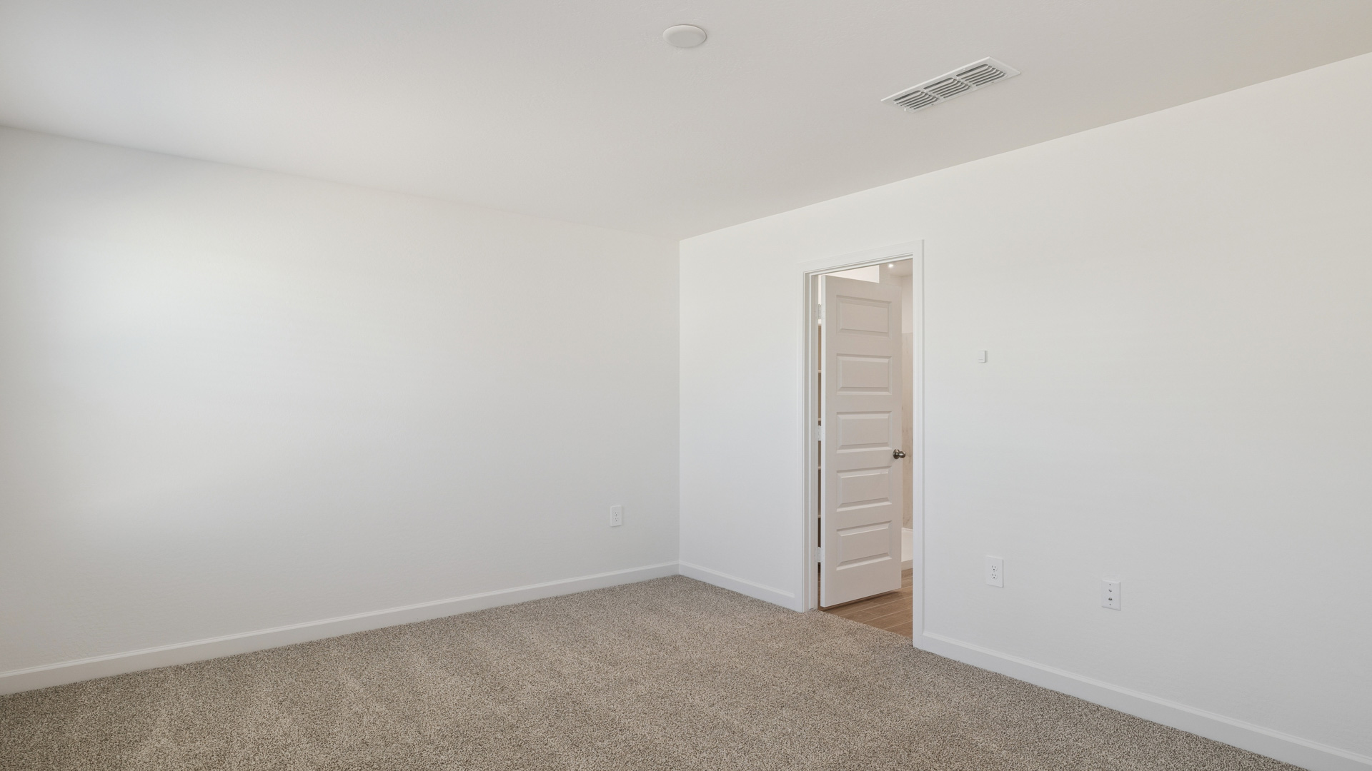 A spacious primary bedroom emphasizing open space and natural lighting.