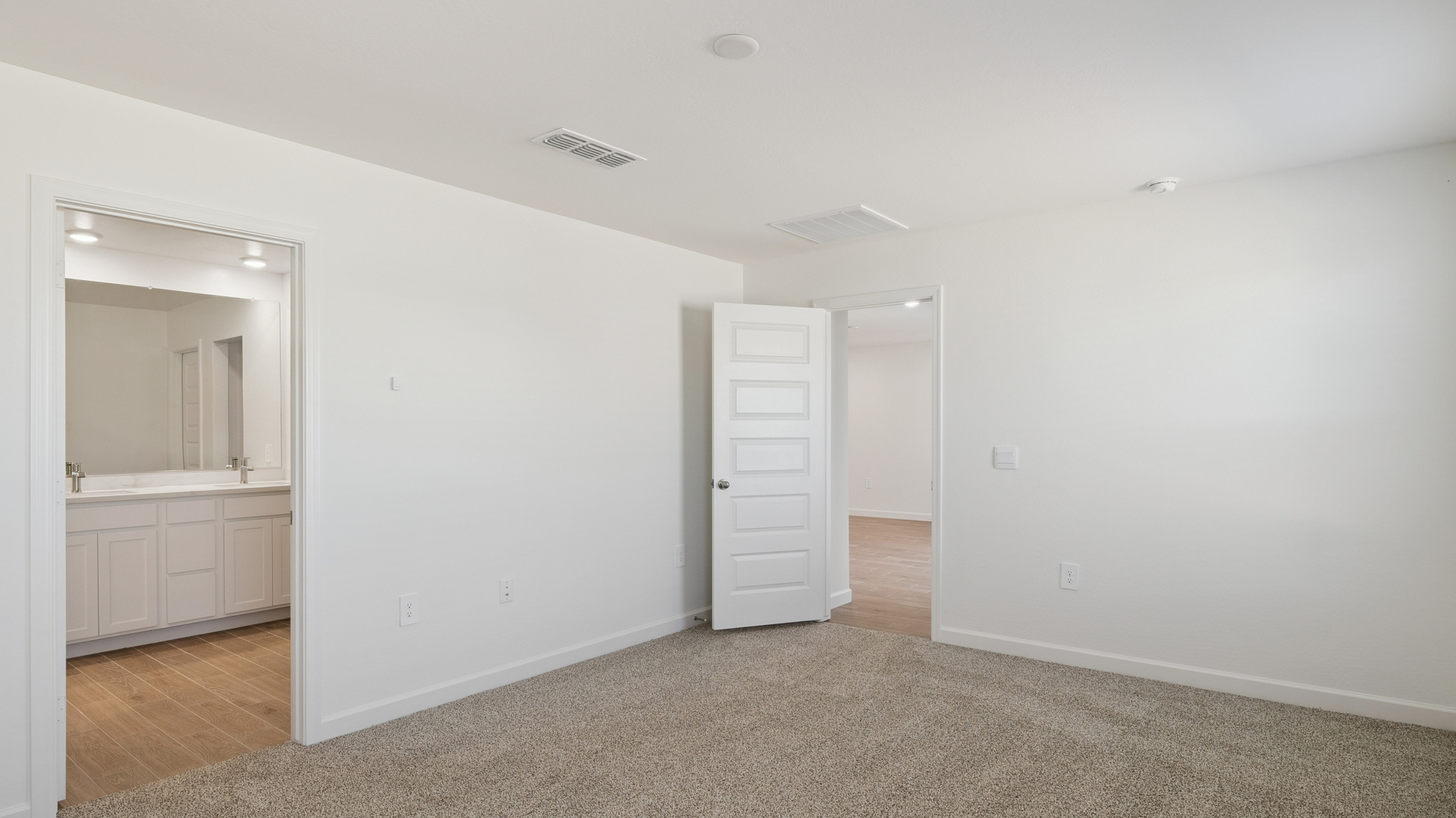 A spacious primary bedroom emphasizing open space and natural lighting.