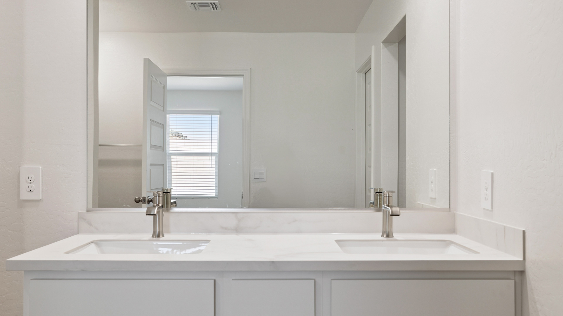 Modern primary bathroom with double vanities, quartz countertops with a walk-in shower and a walk-in closet.