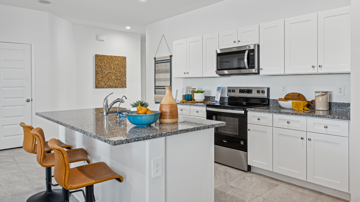Bright and spacious kitchen with granite countertops, stainless steel appliances, and an island with bar seating.