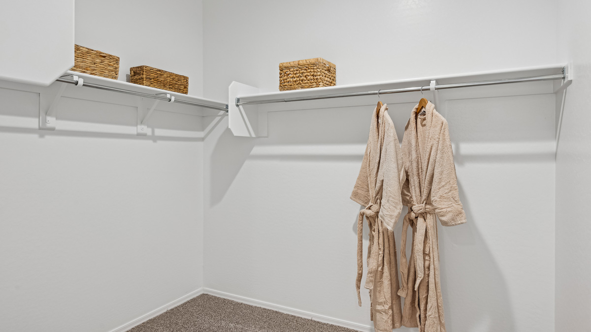 Modern primary bathroom with double vanity, granite countertops with a walk-in shower and a walk-in closet.