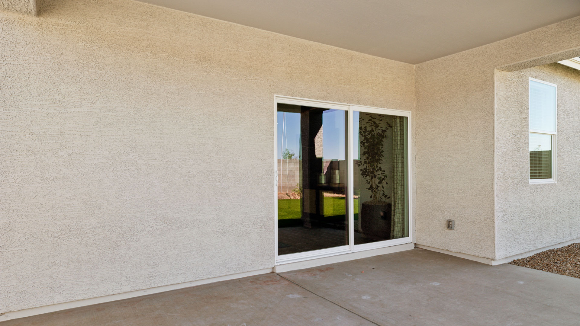 Outdoor covered patio with seating area overlooking a well-maintained lawn, perfect for relaxation.
