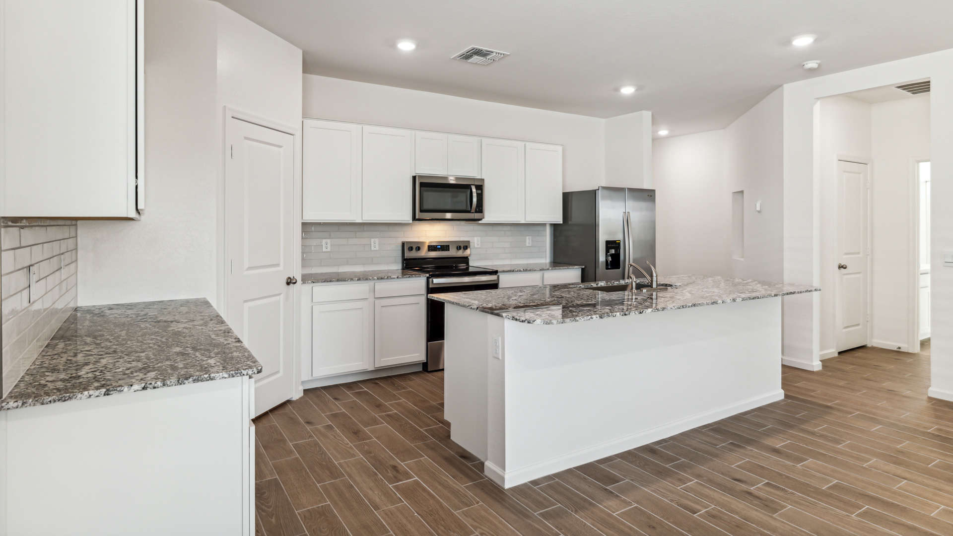 Bright and spacious kitchen with granite countertops, stainless steel appliances, and an island with bar seating.
