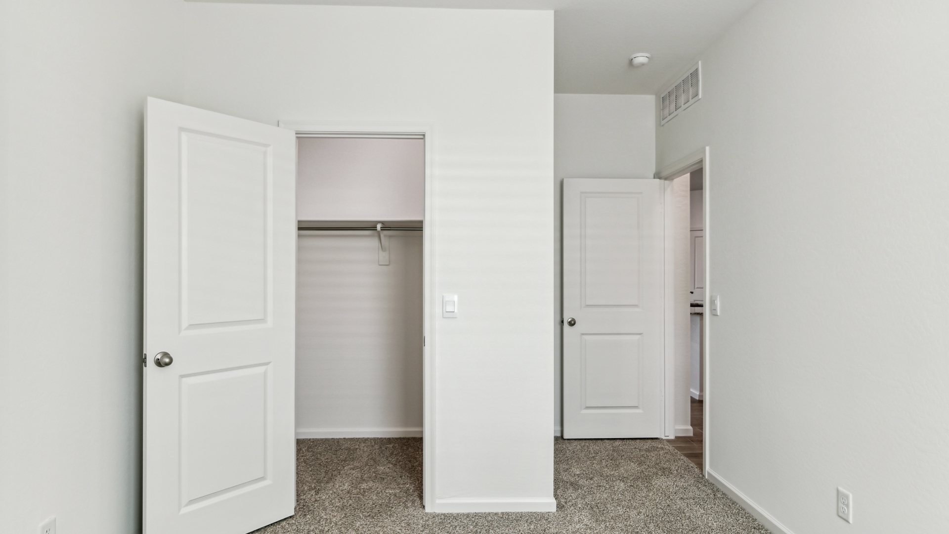 Comfortable guest bedroom featuring neutral-toned walls and a large closet.