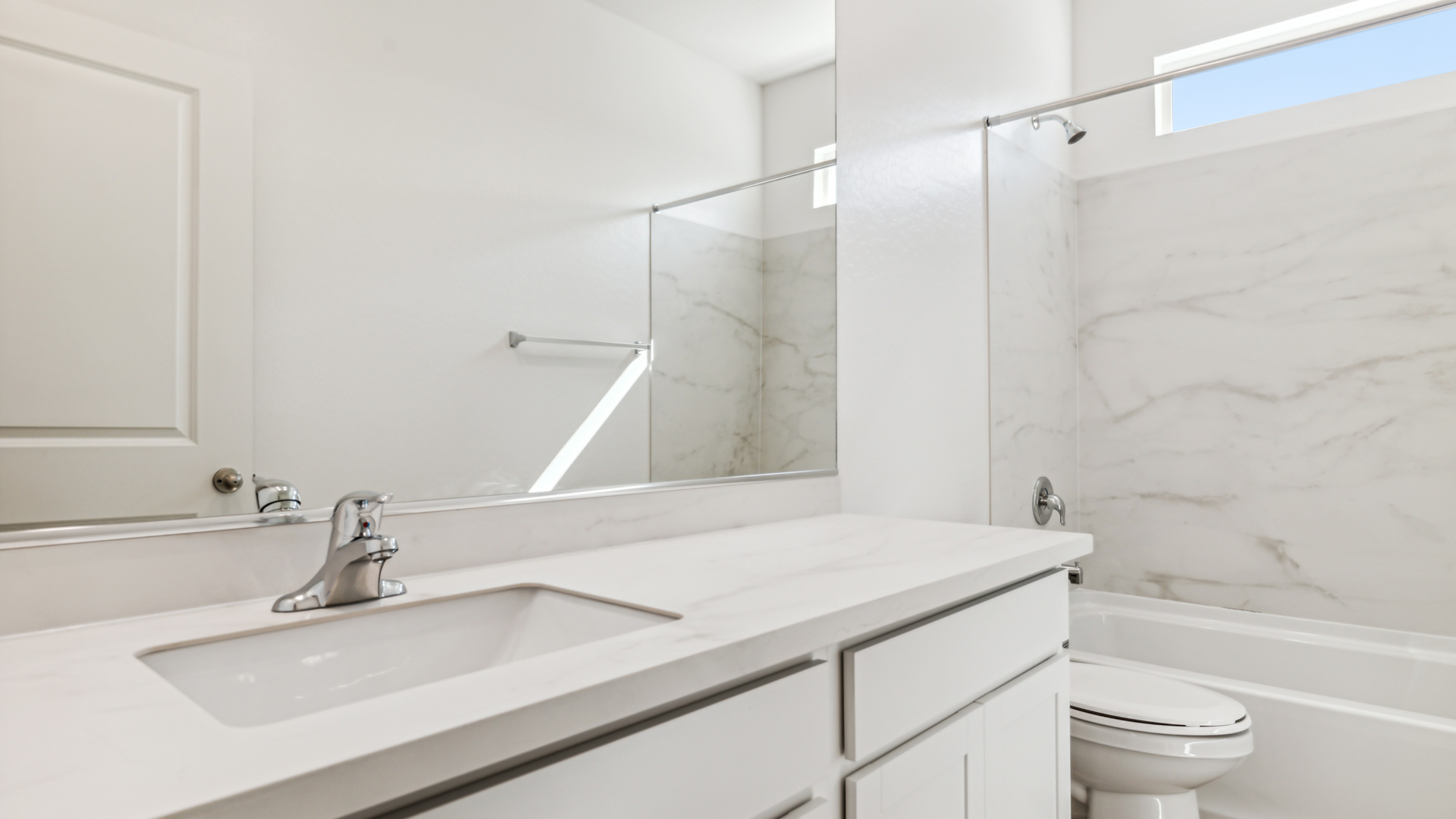 Modern primary bathroom with double vanity, granite countertops with a walk-in shower and a walk-in closet.