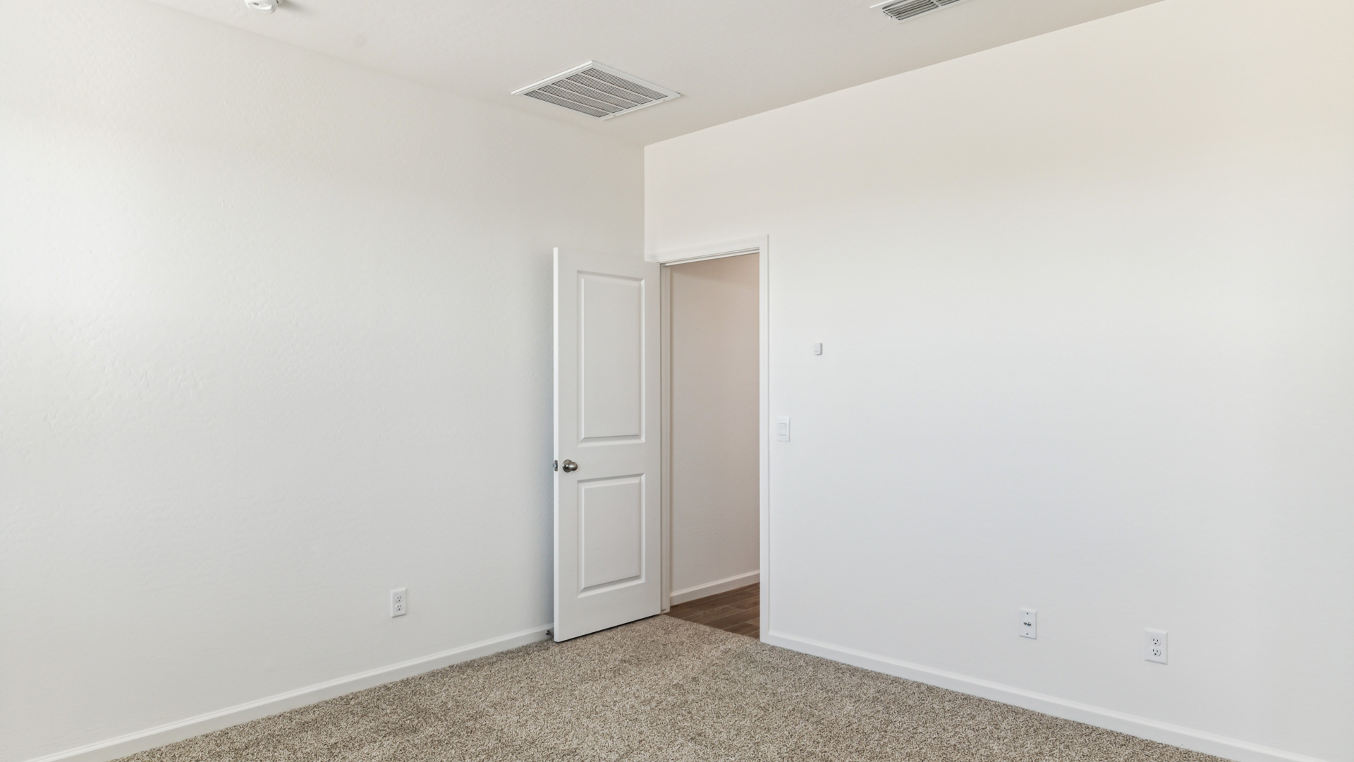 A spacious primary bedroom emphasizing open space and natural lighting.