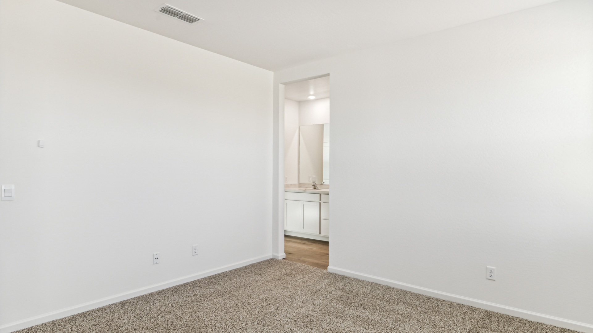 A spacious primary bedroom emphasizing open space and natural lighting.