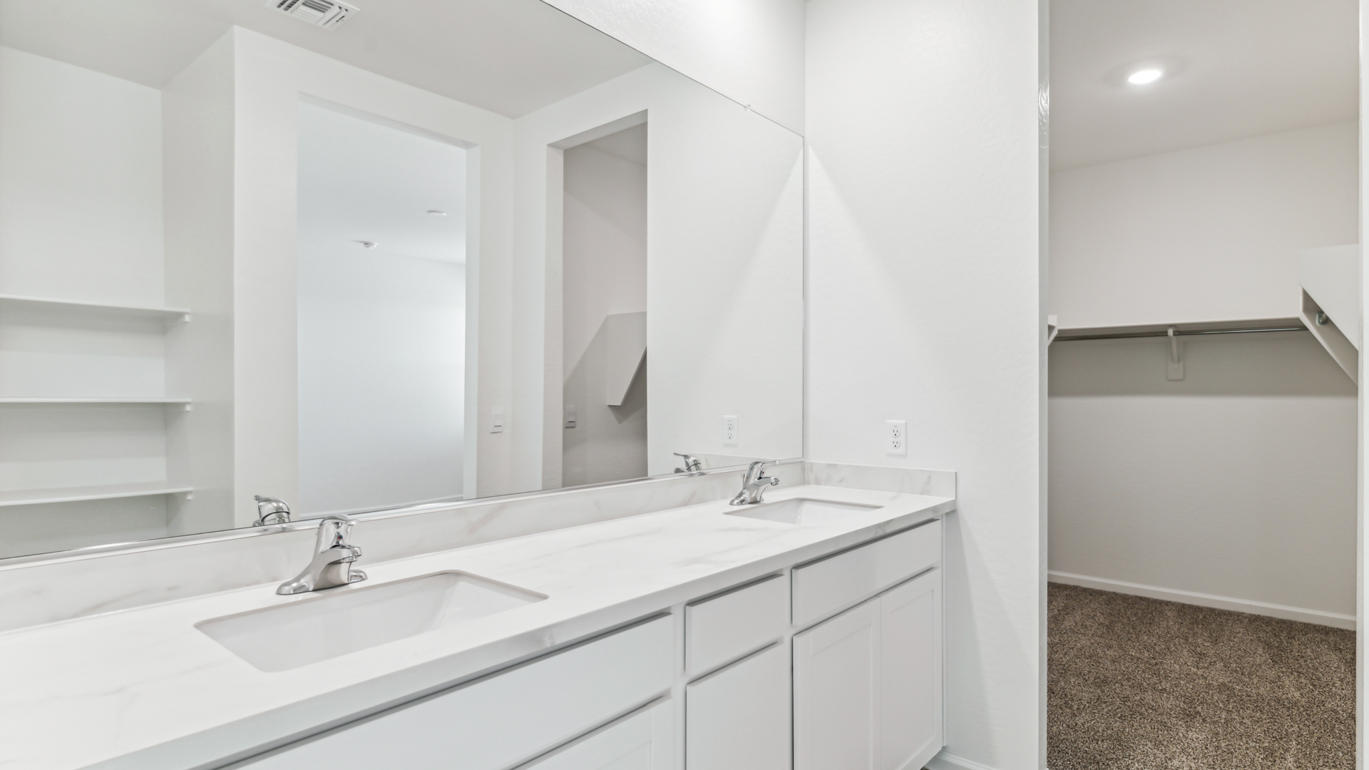 Modern primary bathroom with double vanity, granite countertops with a walk-in shower and a walk-in closet.