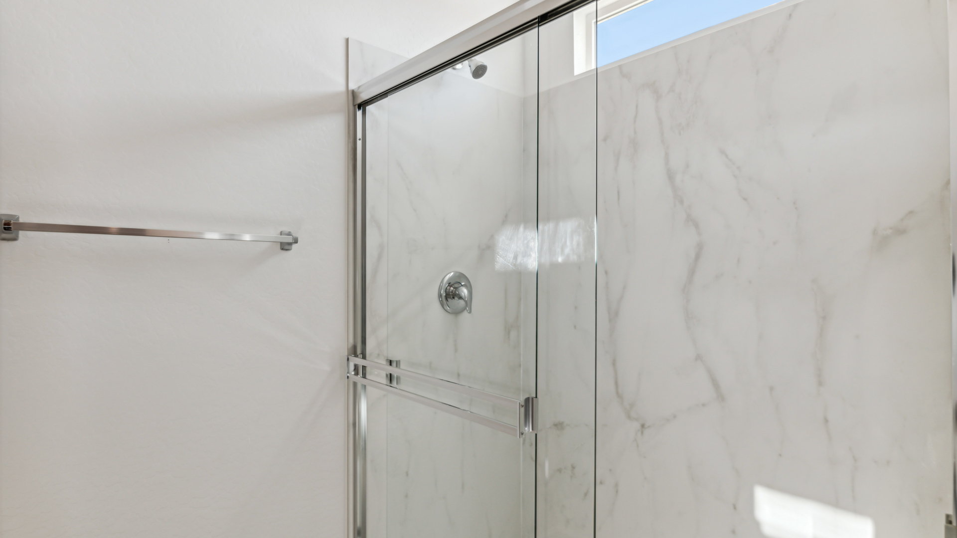 Modern primary bathroom with double vanity, granite countertops with a walk-in shower and a walk-in closet.