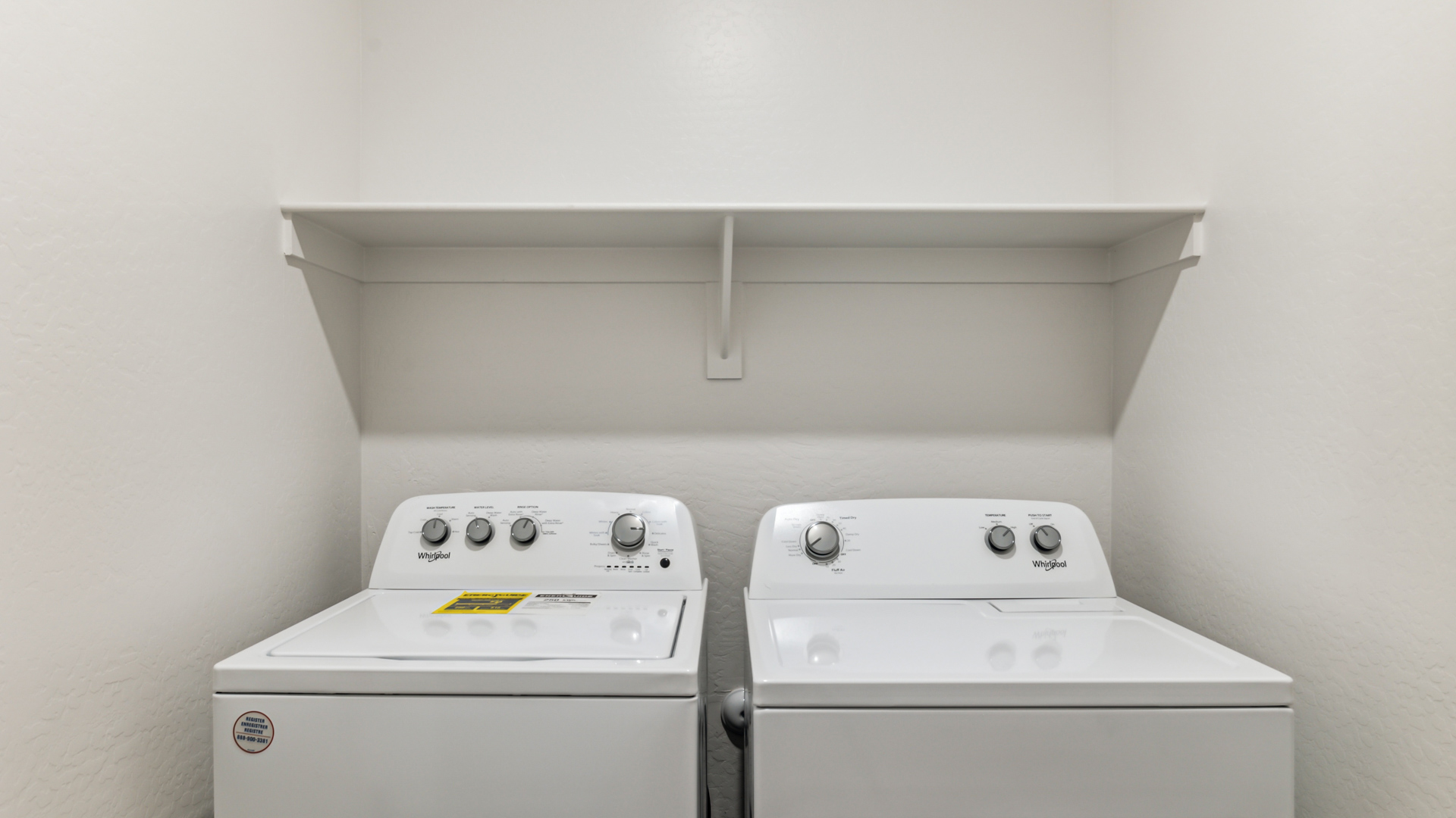 Spacious laundry room with washer and dryer connections and shelving for storage.