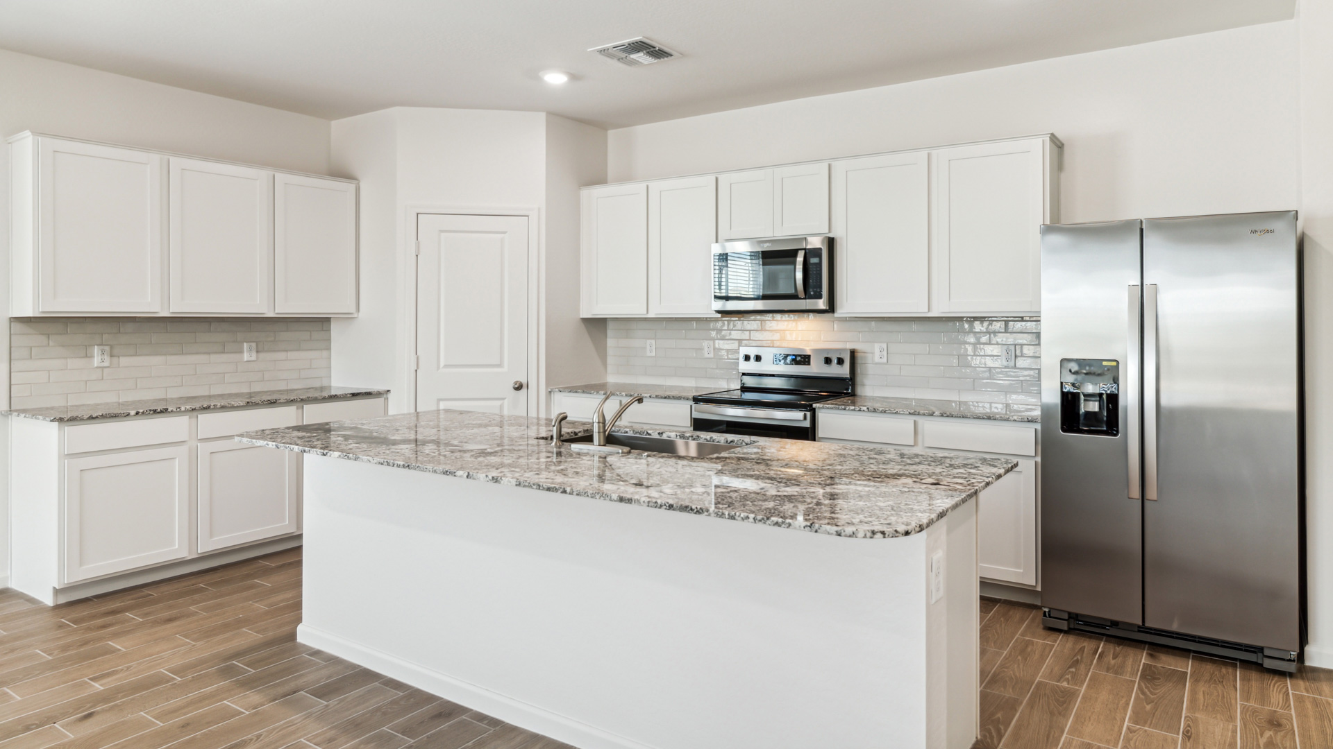 Bright and spacious kitchen with granite countertops, stainless steel appliances, and an island with bar seating.