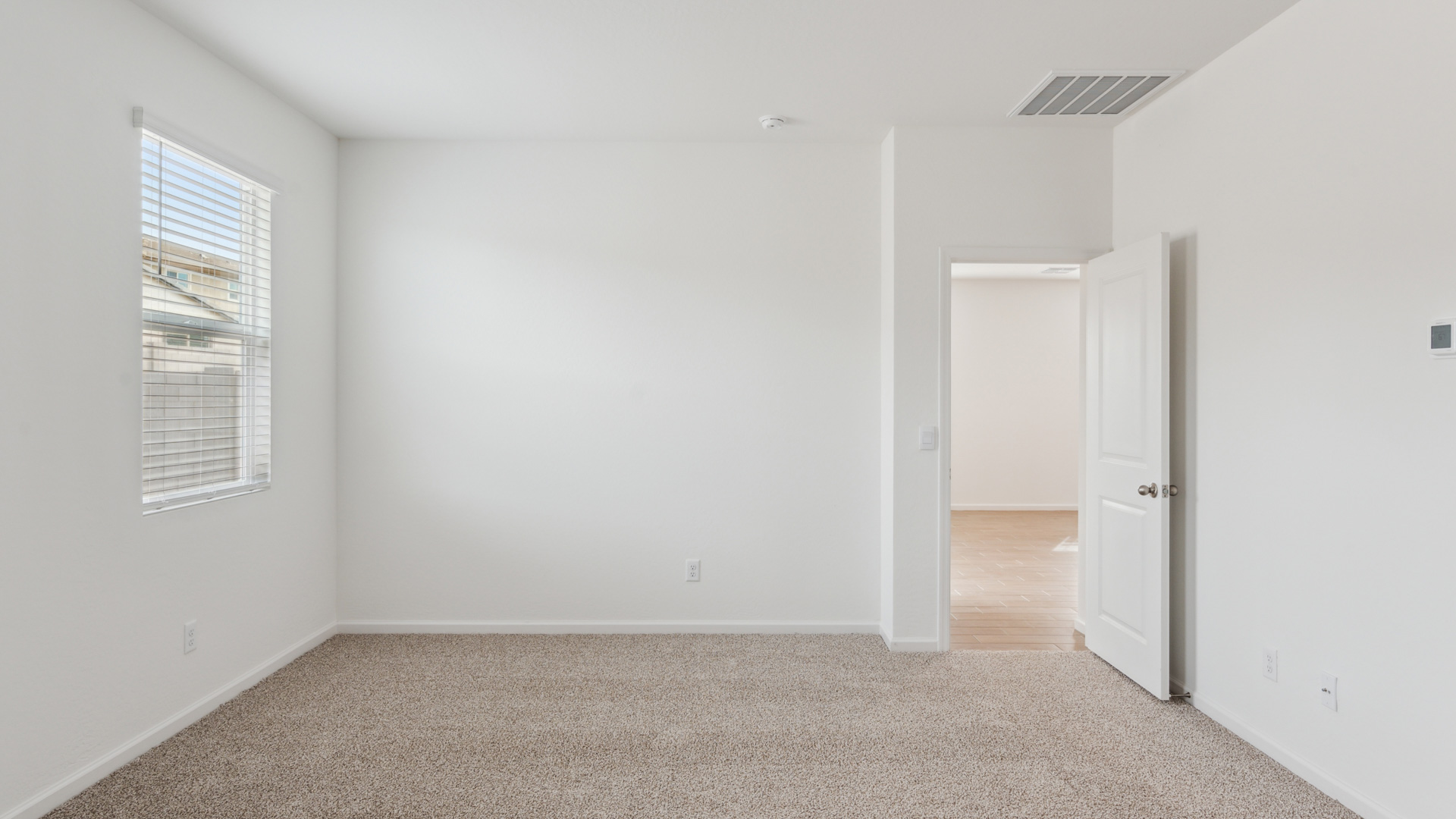 A spacious primary bedroom emphasizing open space and natural lighting.