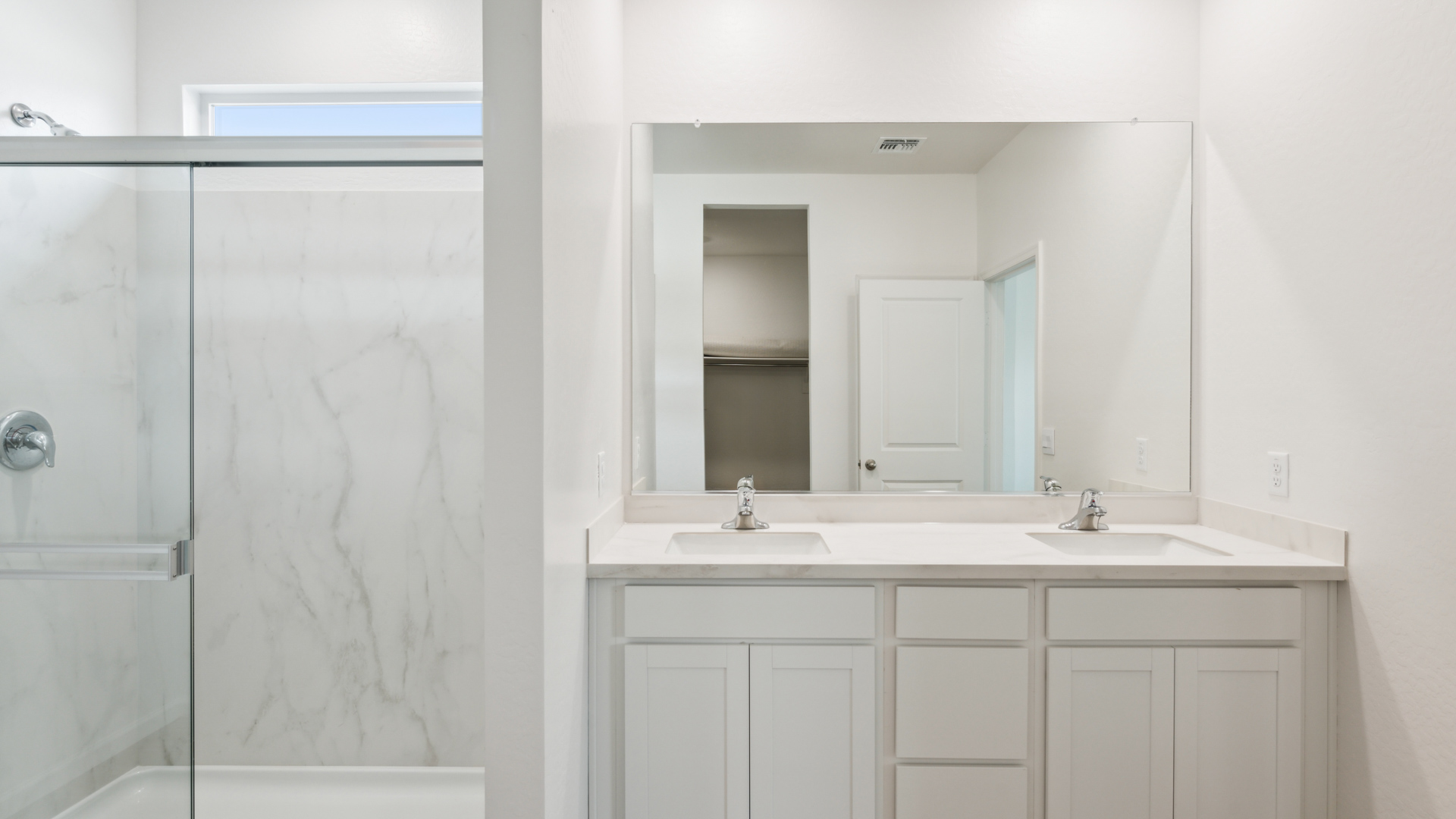 Modern primary bathroom with double vanities, countertops with a walk-in shower and a walk-in closet.