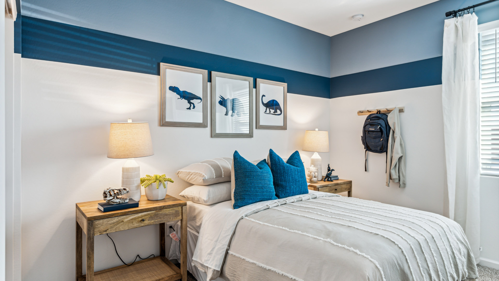 A vibrant kids' bedroom showcasing a neatly made bed, a stylish dresser, and a playful painting that adds charm.
