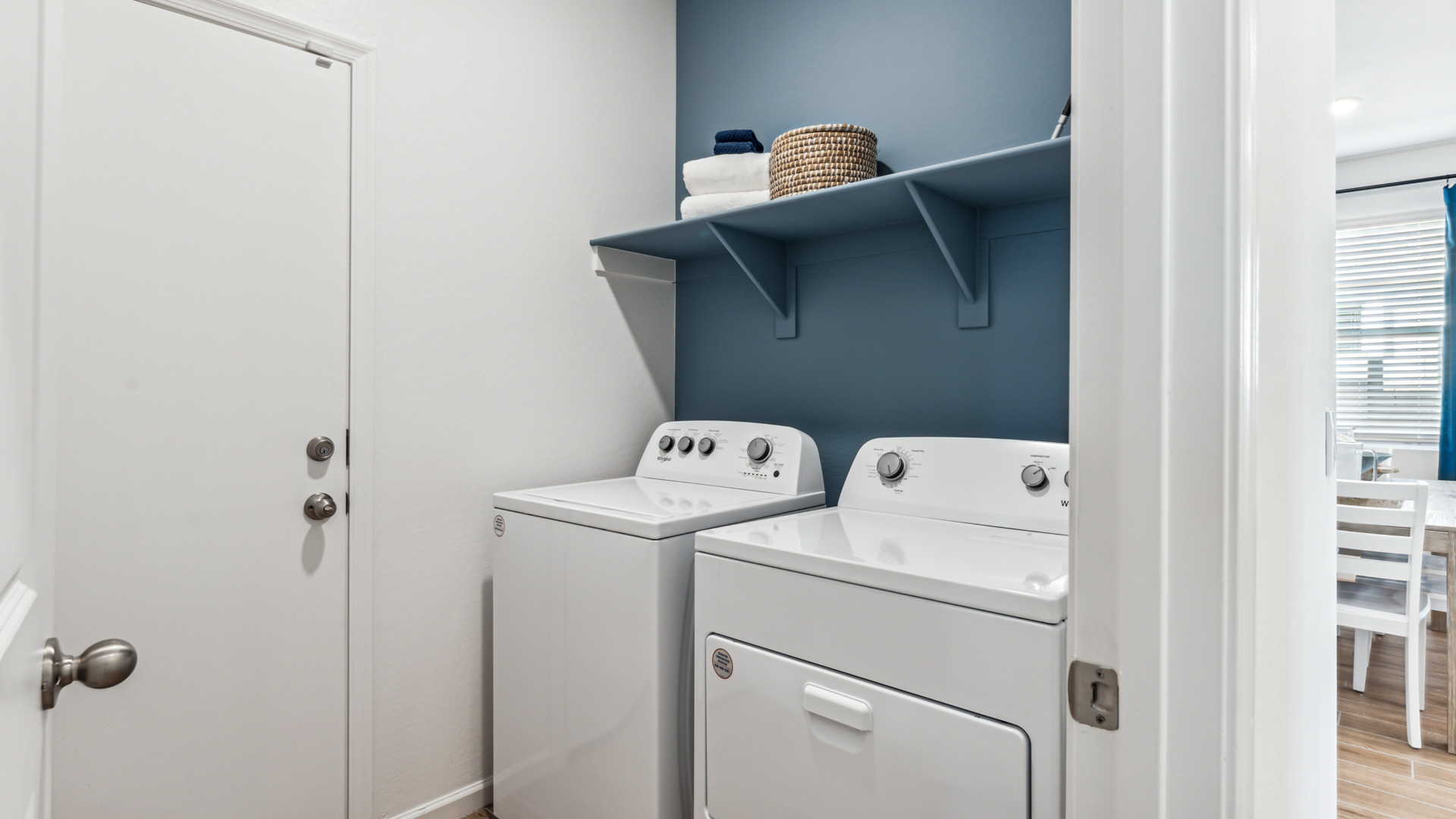 Spacious laundry room with washer and dryer connections and shelving for storage.
